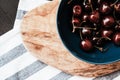 Summer background. Sweet dark cherries in a ceramic bowl, wooden board on a dark background and kitchen towel with a blue line. Royalty Free Stock Photo