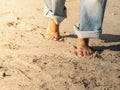 Bare feets. A woman in jeans walks on the sand barefoot.Sunlight summer. Freedom, travel, healthy lifestyle concept