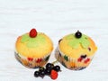 Summer baking - delicious homemade muffins with berries in colorful paper cups, decorated with marzipan cloverleaf and fruits Royalty Free Stock Photo