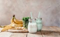 Summer banana smoothie or milkshake with mint and straw in jars on dark wooden tablen with copy space