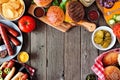 Summer BBQ food frame with hot dog and hamburger buffet, above view over a dark wood background Royalty Free Stock Photo