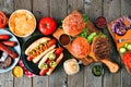 Summer BBQ table scene with hot dog and hamburger buffet, above view on a wood background Royalty Free Stock Photo