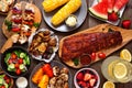 Summer BBQ or picnic food top-down view table scene over a dark wood background