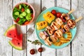 Summer BBQ or picnic food with salad, grilled kabobs, corn and fruit, top view table scene over white wood Royalty Free Stock Photo