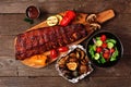 Summer BBQ ribs on a serving board with grilled vegetables, potatoes and salad over wood