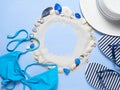 Summer beach bag with elegant women`s accessories on a blue background. White sand and shells. Top view beach bag with Royalty Free Stock Photo