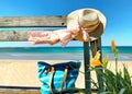 Summer Beach blue sky and sea summer women hat and white scarp with blue handbag on wooden bench seascape yellow flowers