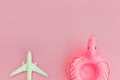 Summer beach composition. Minimal simple flat lay with plane and Inflatable flamingo isolated on pastel pink background. Vacation