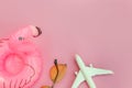 Summer beach composition. Minimal simple flat lay with plane sunglasses and Inflatable flamingo isolated on pastel pink background