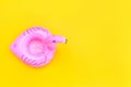 Summer beach composition. Simply minimal design with pink Inflatable flamingo isolated on yellow background. Pool float party,