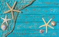 Summer beach holiday, maritime decoration with starfish and seashells in fishing net on blue wooden background Royalty Free Stock Photo