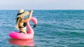 Summer beach relaxing. Happy young sexy girl in bikini swimsuit, sunglasses and straw hat with pink inflatable flamingo in blue Royalty Free Stock Photo