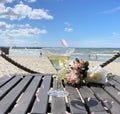 summer beach romantic flowers a bouquet , glass of wine on wooden table,in air flying pink petal view to sea at horizon blue sk