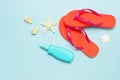 Summer beach sea accessories. Coral flip flops, shells, starfish, yellow sunscreen bottle, body spray on blue background top view Royalty Free Stock Photo