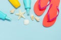 Summer beach sea accessories. Coral flip flops, shells, starfish, yellow sunscreen bottle, body spray on blue background top view Royalty Free Stock Photo