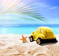 Summer beach with starfish, toy car in white sand and tropical palm leaf Royalty Free Stock Photo