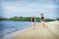 In the summer afternoon on the beach, two girls girlfriends play on the banks of the river Royalty Free Stock Photo