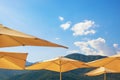 Summer beach vacation, concept. Sun beach umbrellas against mountains and blue sky with light white clouds Royalty Free Stock Photo