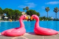 Summer beach vacation. Fashionable, trendy inflatable flamingos on the pool background. Pink pool float