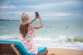 Summer beach vacation holidays trip concept, Happy young Asian woman with hat relaxing and taking a photo and selfie Royalty Free Stock Photo