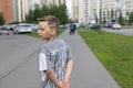 In summer, a beautiful child boy turns over his shoulder on a city street. View from the back of the child. A child Royalty Free Stock Photo