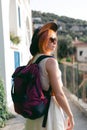 Summer is a beautiful day. A girl in a white dress and hat walks along the narrow streets of Italy. Backpack behind. Travel and Royalty Free Stock Photo