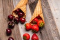 Fresh strawberries and cherries in waffle cones on wooden table Royalty Free Stock Photo