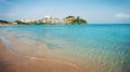 Summer blue coastal beach with building and vegetation on the background