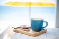 Summer blue coffee Latte cup by the beach with yellow umbrella background