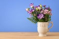 summer bouquet of purple flowers in the vase over wooden table and blue background. Royalty Free Stock Photo