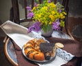 Summer bouquet of yellow and purple wild flowers in an earthenware gray vase and a plate of fruit and cereal chips