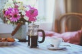 Summer breakfast in cozy country house. Table with bouquet of flowers from own garden, french press with coffee and cookies. Royalty Free Stock Photo