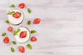 Summer breakfast with sliced strawberry, leaves mint on white wood board, top view. Decorative border with copy space.