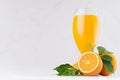 Summer bright citrus juice with group oranges, round slice and young green leaves on white modern kitchen interior. Royalty Free Stock Photo