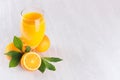 Summer bright citrus juice with group oranges, round slice and young green leaves on white wood board, top view, copy space. Royalty Free Stock Photo