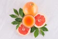 Summer bright fresh pink cocktail of grapefruits with green leaves, slice grapefruit on white wooden background, top view.