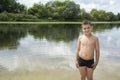 Summer bright sunny day boy stands in water.