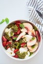 Summer burrata salad with peaches, cherry tomatoes, pesto and spices in bowl on white background