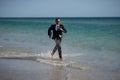 Summer business. Freelancer run on summer sea beach. Businessman in wet suit jump in sea water. Crazy business summer