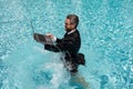 Summer business in swimming pool. Business man in suit and laptop splash water in swimming pool. Crazy summer business