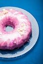 Summer cake with sugar pink glaze on a glass plate. Blue background