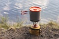 Summer camping in the open air, against the background of the lake. Tourist gas burner with pans for cooking Royalty Free Stock Photo