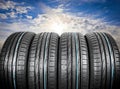 Summer car tires on over blue sky with clouds. Tire stack background. Car tyre protector close up. Black rubber tire. Brand new Royalty Free Stock Photo
