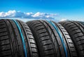 Summer car tires on over blue sky with clouds. Tire stack background. Car tyre protector close up. Black rubber tire. Brand new Royalty Free Stock Photo
