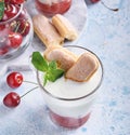 Summer cherry puff pastry with savoiardi cookies and cream cheese in glass on light grey background. Traditional tiramisu cake