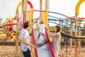 Summer, childhood, leisure and family concept - happy child and his parents on children playground climbing frame Royalty Free Stock Photo