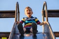 Summer, childhood, friendship and people concept - happy little boy on children playground slid from the hill Royalty Free Stock Photo