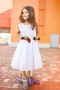 Summer, childhood and people concept - little girl on scooter