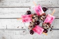 Summer chocolate and nut dipped cherry popsicles on a plate against rustic white wood Royalty Free Stock Photo