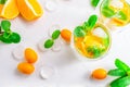 Summer citrus drink with orange, kumquat, mint and ice cubes on white background. Flat-lay, top view